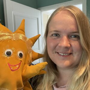 Auri käsinukke ja aikuinen pitämässä nukkea